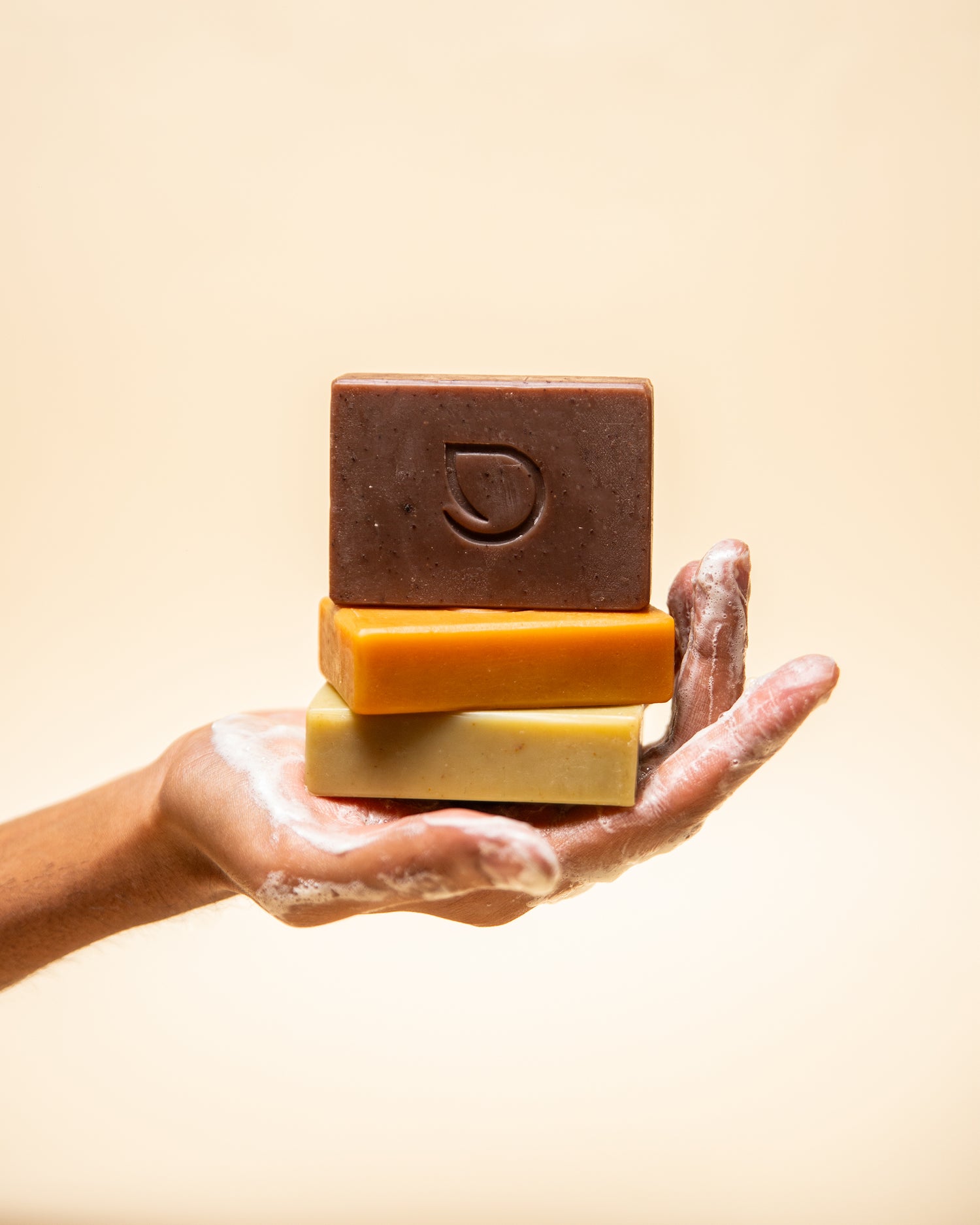 A hand holding stack of three darzata soaps