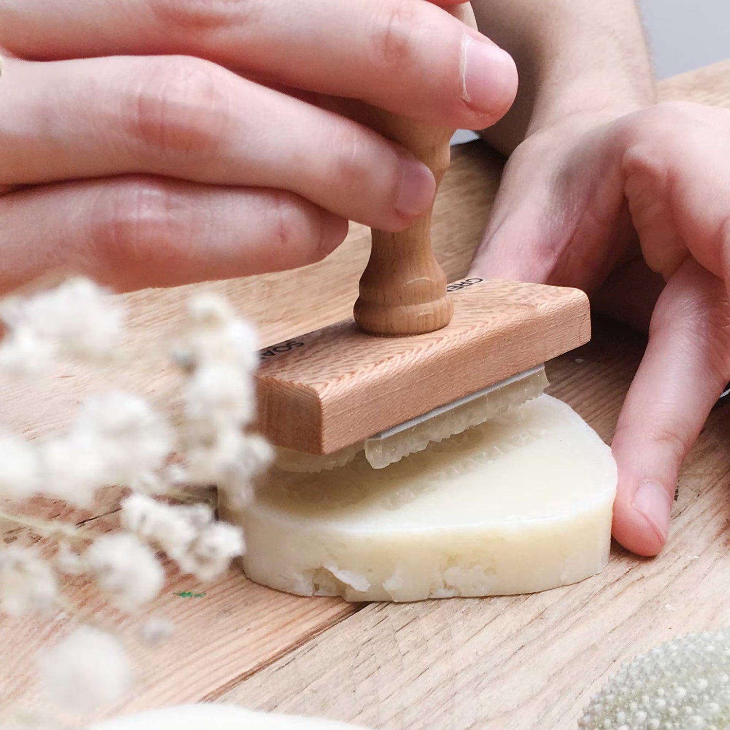 Hands stamping soap with customised wooden stamp